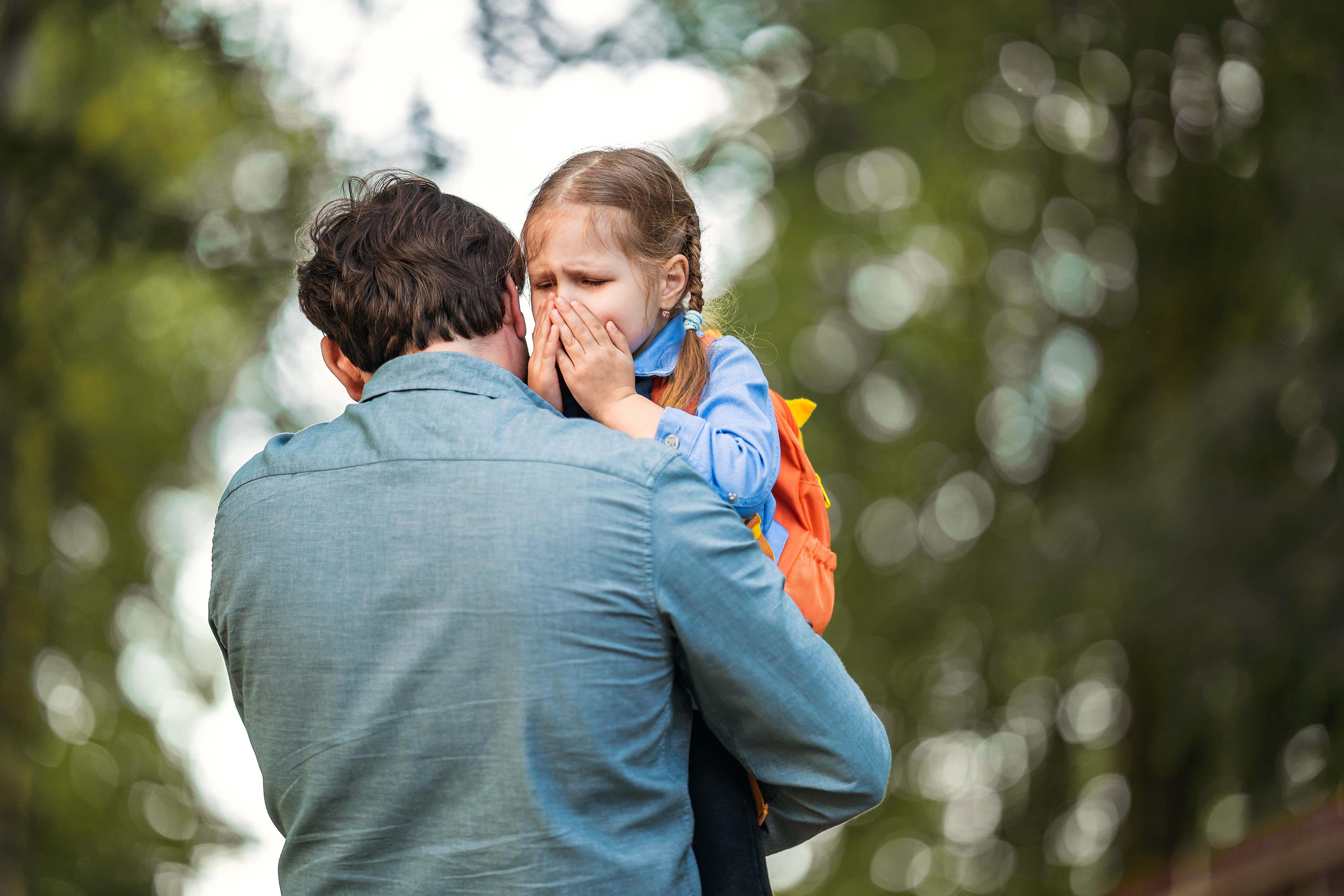 A man holding a crying young girl | Source: Shutterstock