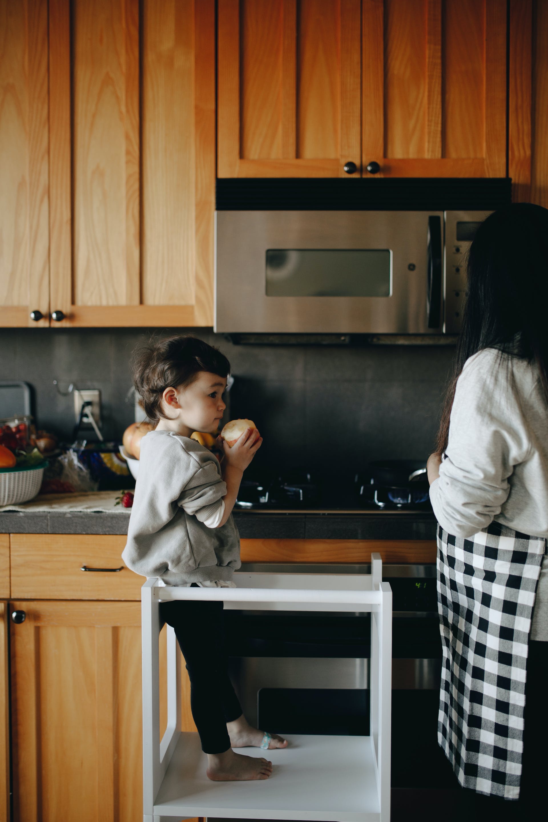 A little boy standing beside his mom in the kitchen | Source: Pexels