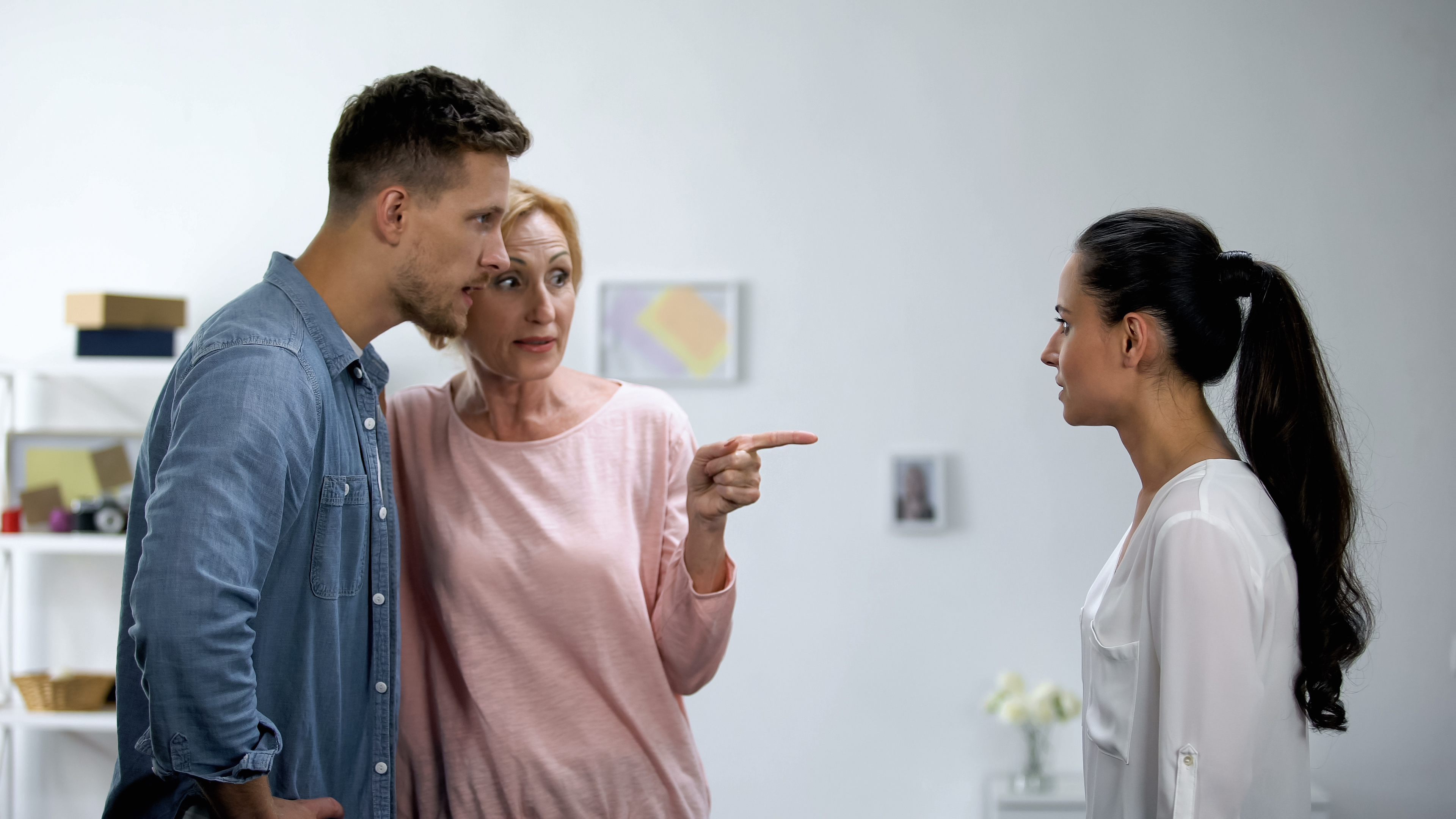 A woman standing with her son while she points at his girlfriend | Source: Getty Images