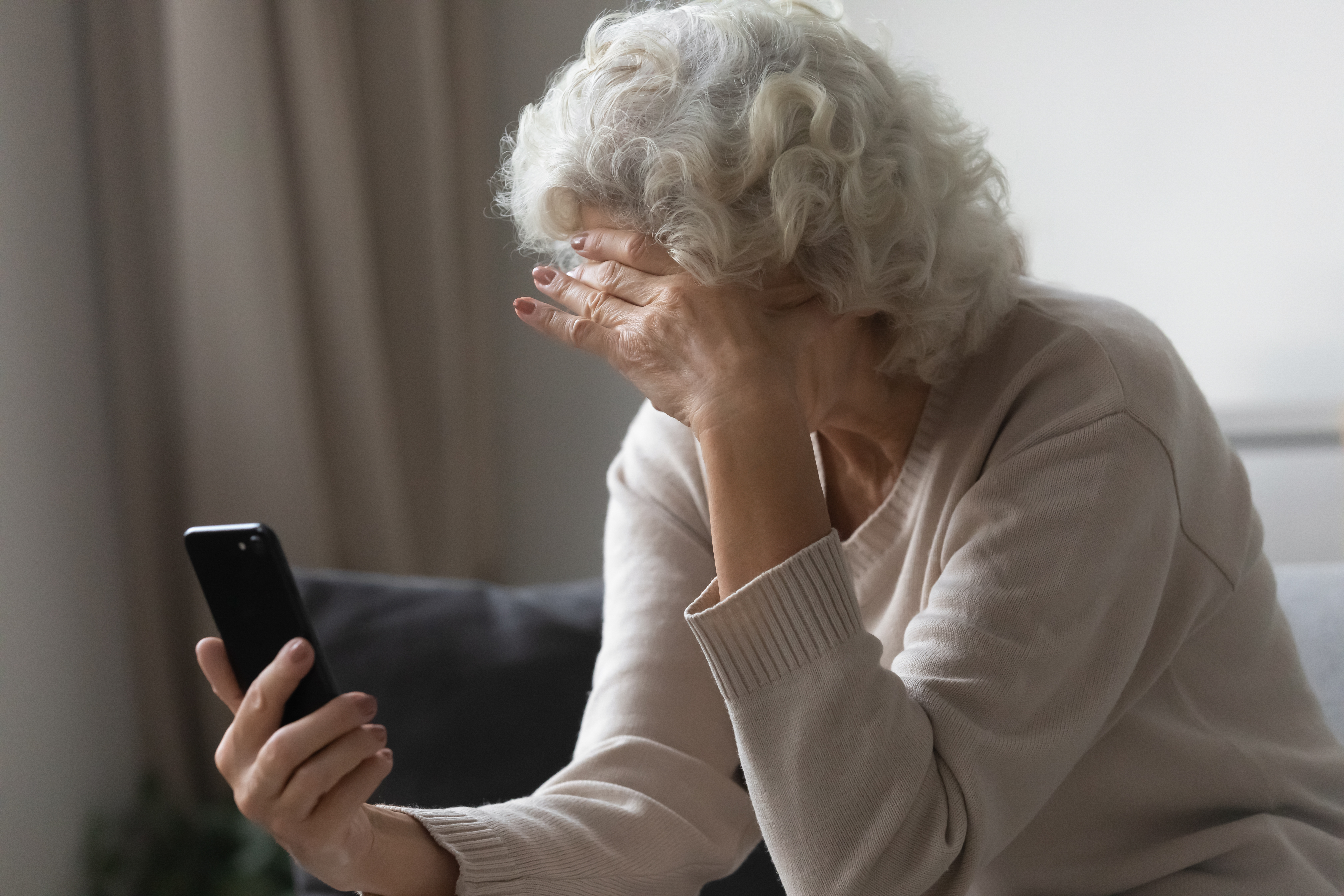 An older woman looks concerned while holding a cell | Source: Shutterstock